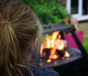 Rear view of woman looking at fire pit burning in yard