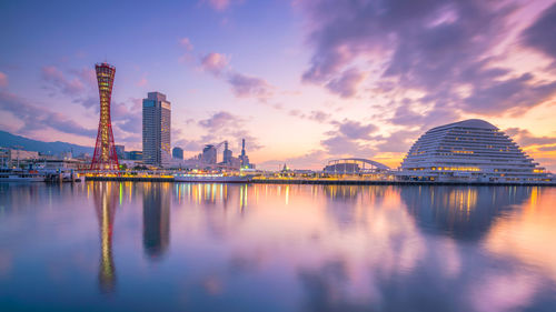 Reflection of illuminated buildings in lake during sunset