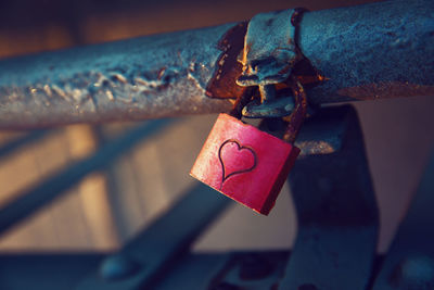 Close-up of padlock with heart shape attached on metallic railing