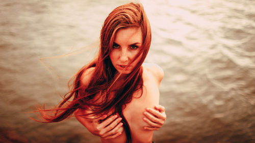 Portrait of young woman standing against wall