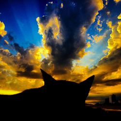 Silhouette of landscape against cloudy sky at sunset