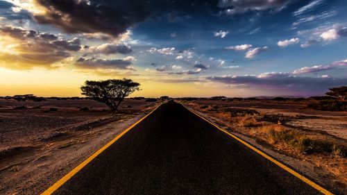 Road by illuminated street against sky at night