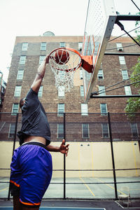 Man playing basketball hoop against buildings in city