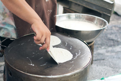 Midsection of woman pouring batter on frying pan