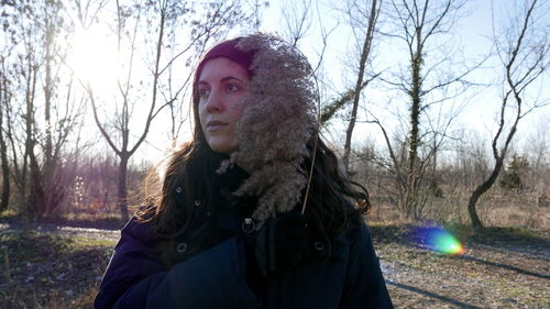 Portrait of woman against bare trees in winter