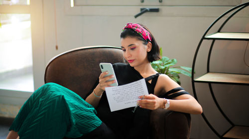 Young woman using mobile phone while sitting in office