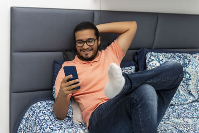 Young man using mobile phone while sitting on sofa