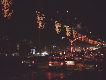 Cars on illuminated city street at night