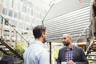 Businessmen discussing outside log cabin at office yard