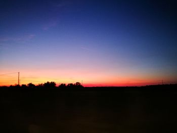 Scenic view of silhouette trees against clear sky at sunset