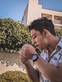 Side view of young man holding cigarette