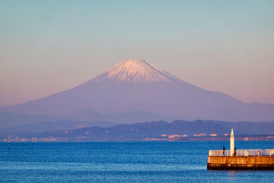 Scenic view of sea and snowcapped mountains against sky during sunrise