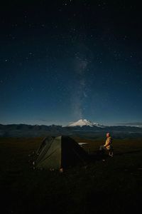 Rear view of woman standing on mountain against sky at night