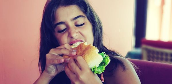 Girl with eyes closed biting food