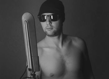 Portrait of shirtless man standing against black background