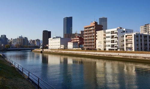 River and buildings against clear sky