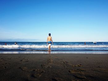 Man with surfboard walking on beach