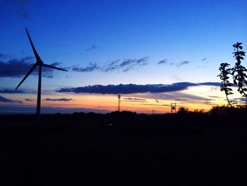 Wind turbines on field against sky at sunset