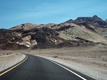 Road leading towards mountains against sky