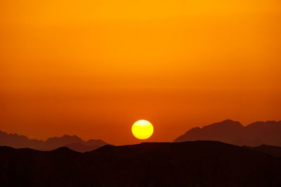 Scenic view of silhouette mountains against orange sky