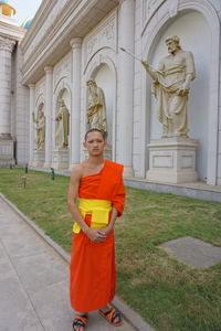 Portrait of smiling monk standing against building