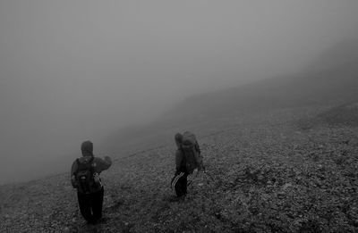 Rear view of people walking on mountain against sky