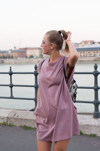 Woman standing by railing against sky in city