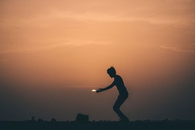 Silhouette man jumping against sky during sunset