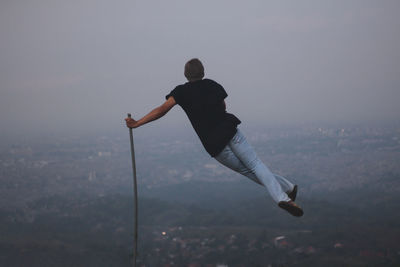 Rear view of man balancing on stick