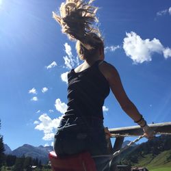 Low angle view of woman enjoying swing against sky