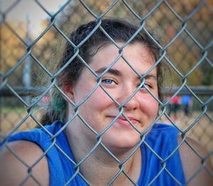 Close-up portrait of  female athlete behind chainlink fence in dugout