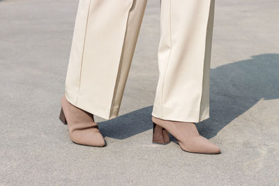 Female legs in trousers and autumn shoes on a concrete close-up.