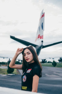 Portrait of young woman standing on road against the sky
