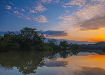 Reflection of trees in lake against sky during sunset