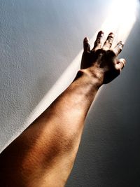 Midsection of person touching shadow on wall