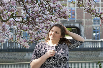 Portrait of a beautiful plump caucasian confident woman in magnolia flowers