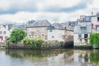 Buildings by river against sky