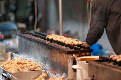 Midsection of man preparing food on barbecue grill