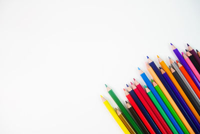 Close-up of colored pencils over white background