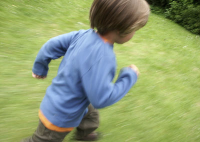 High angle view of boy running on grassy field at park