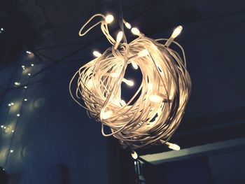 Low angle view of illuminated light bulb hanging from ceiling