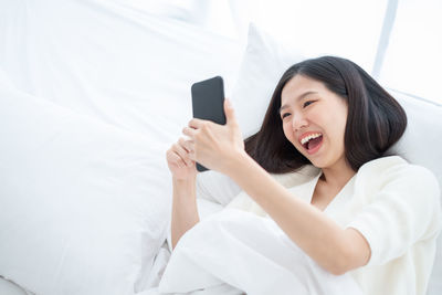 Young woman using mobile phone on bed