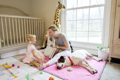 A mom and daughter reading a book, dog sleeping next to them