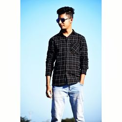 Young man wearing sunglasses standing against clear sky