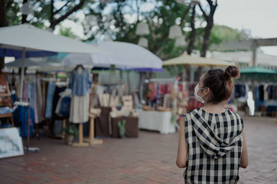 Back view point young women wear mask touring in street market , chiang mai north of thailand