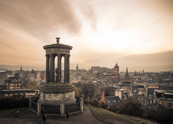 Historic structure overlooking cityscape against cloudy sky