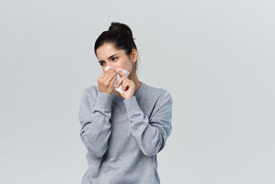 Portrait of young woman standing against white background