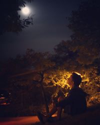 Silhouette man and tree against sky at night