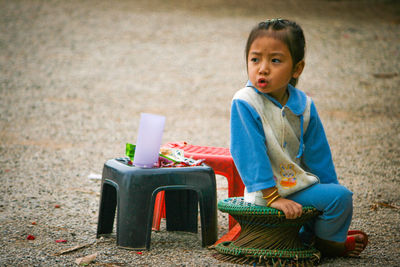 Cute boy looking away while sitting on toy