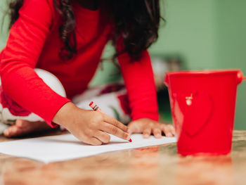 Midsection of woman holding red while sitting on table